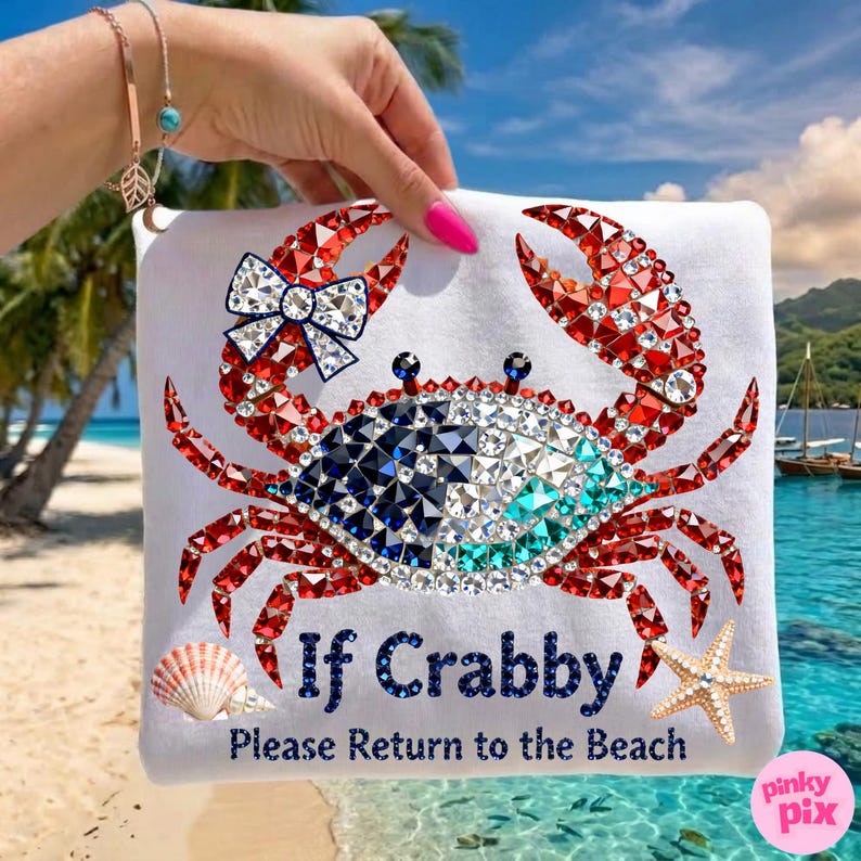 May include: White t-shirt featuring a crab design made of red, blue, and clear crystals. The crab has a bow and the text "If Crabby Please Return to the Beach". A seashell and starfish are also shown.