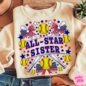 May include: Cream-colored sweatshirt with a softball-themed design. The design includes yellow softballs, crossed baseball bats, red and blue stars, and the text "ALL-STAR SISTER" in blue. Patriotic bows complete the design.