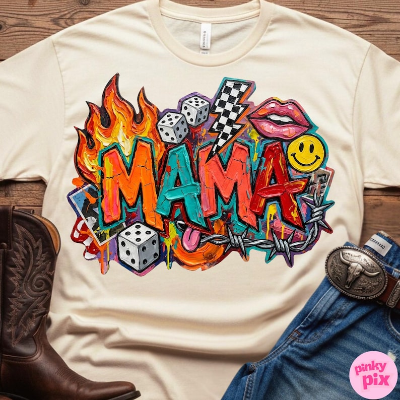May include: Cream-colored t-shirt with a vibrant graphic design. The design features the word "MAMA" in bold, graffiti-style lettering, surrounded by flames, dice, a lightning bolt, lips, a smiley face, and barbed wire. The shirt is paired with jeans and a cowboy boot.