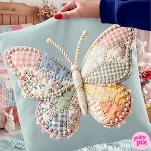 Könnte beinhalten: Hellblaues Zierkissen mit einem großen Schmetterlingsdesign. Der Schmetterling besteht aus Patchwork-Stoff in Pastellfarben mit Perlenbesatz. Der Körper und die Fühler des Schmetterlings sind aus gedrehtem Seil gefertigt.