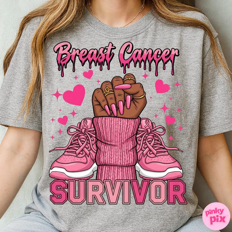 May include: Gray t-shirt with a pink graphic design. The design includes the words "Breast Cancer Survivor" above a raised fist, pink sneakers, and pink hearts. The text and design elements are in shades of pink.