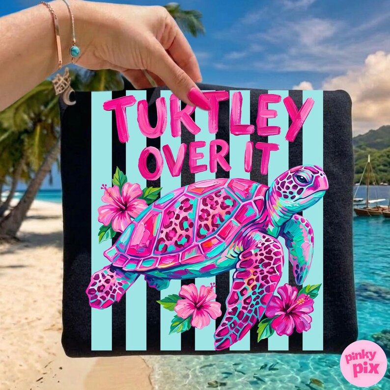 May include: A black tote bag with a colorful design featuring a pink and blue sea turtle, pink hibiscus flowers, and the text "Turtley Over It" in pink. The background has light blue stripes.