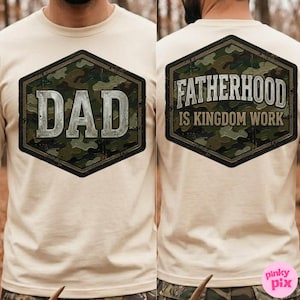 Pode incluir: Camiseta bege com um design de camuflagem em forma de hex&aacute;gono. A frente da camisa tem a palavra "DAD" em uma fonte prateada desgastada. A parte de tr&aacute;s da camisa tem o texto "FATHERHOOD IS KINGDOM WORK".