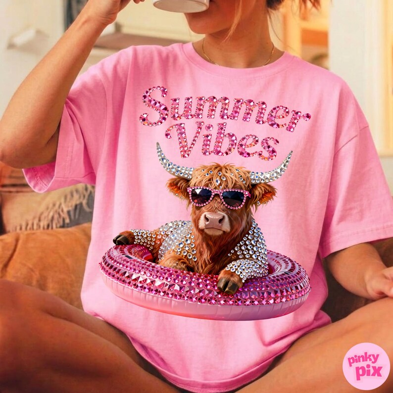 May include: Pink t-shirt with the text "Summer Vibes" in a sparkly font. The shirt features a graphic of a Highland cow wearing sunglasses and a bejeweled floatie. The cow is also adorned with rhinestones.