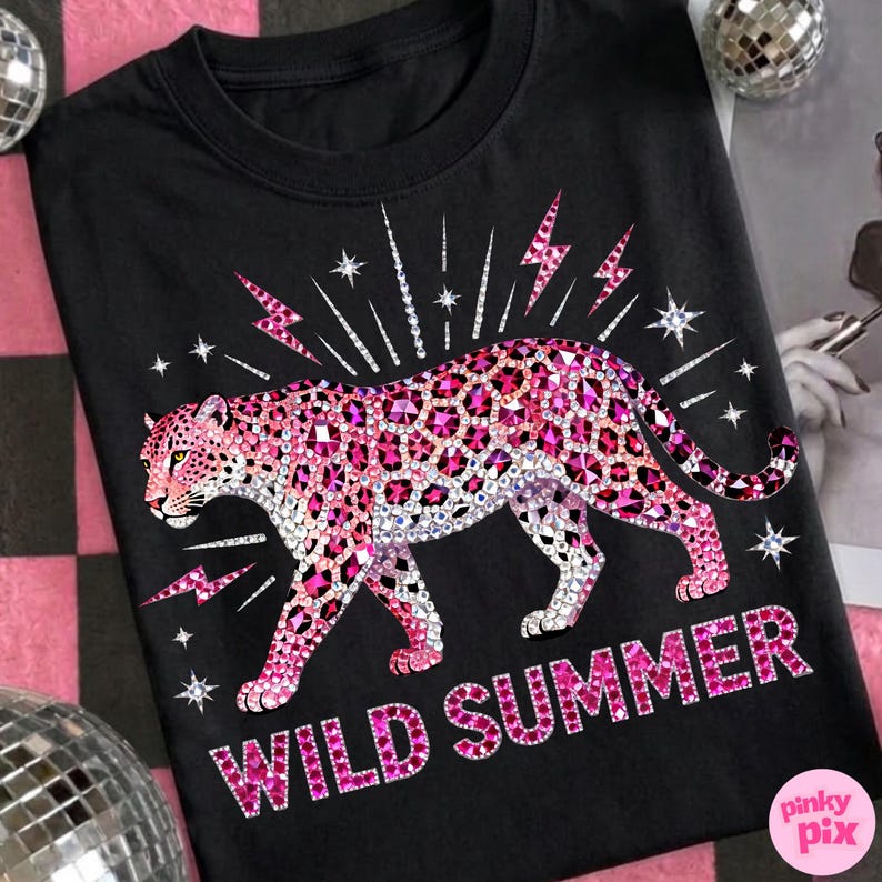 May include: Black t-shirt featuring a pink leopard design with sparkling accents and the words "WILD SUMMER". The leopard is adorned with pink and clear crystals, and the design includes lightning bolts and stars.