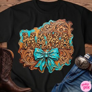 May include: Black t-shirt featuring a decorative design with the word "MAMA" in leopard print. The design includes a turquoise bow and a brown, ornate background, evoking a Western or country theme.
