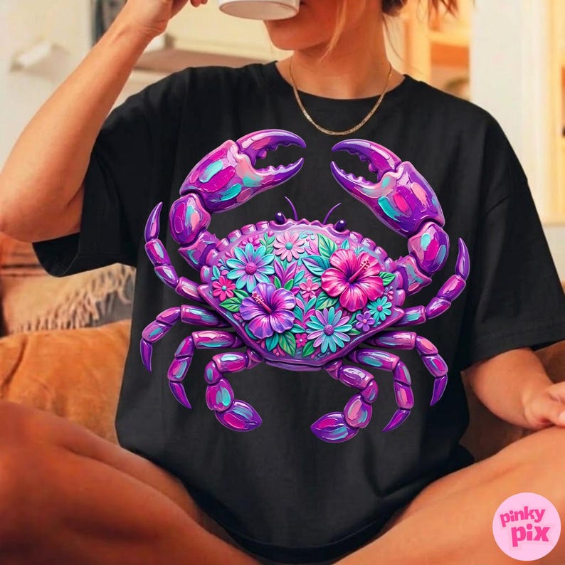 May include: Black t-shirt featuring a vibrant, stylized crab design. The crab is rendered in shades of purple, pink, and teal, with floral accents. The design is centered on the shirt, creating a bold and eye-catching graphic.