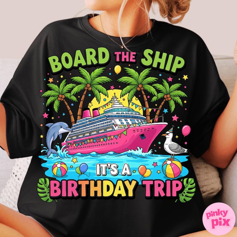 May include: Black t-shirt with a vibrant graphic of a pink cruise ship, palm trees, a dolphin, and a seagull. Text says "BOARD THE SHIP" and "IT'S A BIRTHDAY TRIP" in bright colours. Balloons and stars are also included in the design.