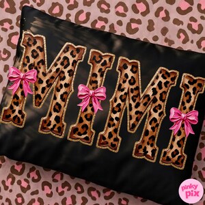 May include: Black rectangular pillow with the word "MIMI" in leopard print letters outlined in gold glitter. Pink bows are attached to the letters. The pillow is on a pink and brown leopard print background.