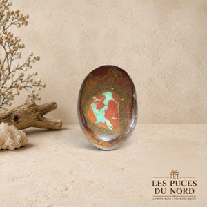 Peut inclure: Une pierre polie de forme ovale présentant un extérieur brun foncé et brun rougeâtre avec une inclusion centrale irrégulière et proéminente de dépôts minéraux turquoise vif et orange brillant, à la surface lisse et réfléchissante.