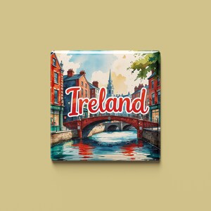 以下が含まれることがあります： アイルランドの運河にかかる橋の水彩画。橋は赤く、アーチがいくつかあります。運河の両側には建物があり、画像の上部には赤い文字で「アイルランド」と書かれています。