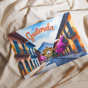 Peut inclure: Aquarelle de Guatemala avec des bâtiments colorés, une montagne et le mot "Guatemala" en écriture orange. L'œuvre est sur fond blanc avec des épis de blé.