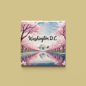 以下が含まれることがあります： ワシントンD.C.の水彩画を描いた正方形の画像。ジェファーソン記念館が水面に映り、桜の木々に囲まれています。「Washington, D.C.」の文字が上部に書かれています。