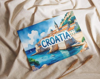 May include: Watercolor postcard featuring a coastal scene of Croatia, with the word "CROATIA" in a blue bubble font. The image depicts buildings with orange roofs, a church tower, and boats on the turquoise water. The postcard is on a beige fabric.