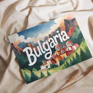 May include: A watercolor print featuring the word "Bulgaria" in white script. The image depicts a mountain range, a church with red domes, and green trees. The print is resting on a beige fabric.