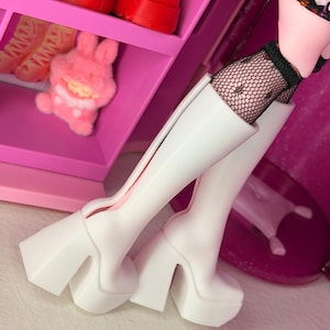 May include: A pair of white platform boots with a chunky heel. The boots are knee-high and have a sleek, modern design. The image also shows a pink shelf with red shoes and a pink plush bunny.