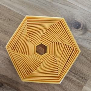May include: A set of 12 yellow hexagon-shaped cookie cutters, nested inside each other, creating a spiral pattern.