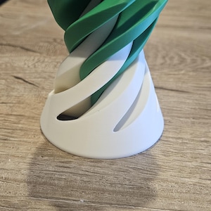 以下が含まれることがあります： 白いベースと緑のトップを持つ3Dプリントされたオブジェクト。オブジェクトはらせん状で、滑らかで光沢のある仕上げになっています。