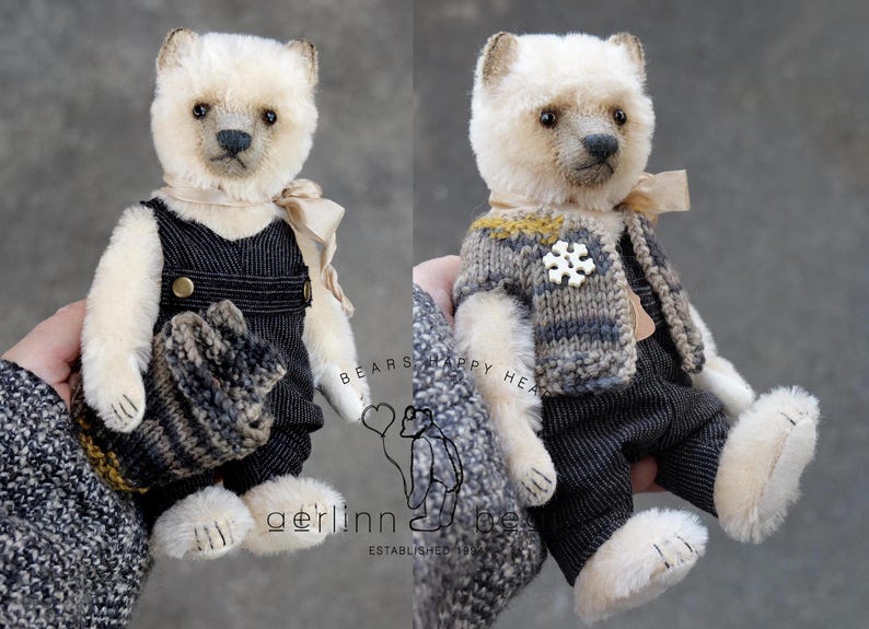 May include: A cream-colored plush bear with dark eyes and a stitched nose, wearing black pinstriped overalls and a beige ribbon. The bear is shown with a gray and brown knit vest featuring a white snowflake button. Text reads BEARS HAPPY HEART.