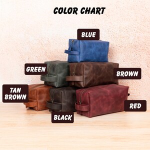 Op de afbeelding: Een kleurenkaart toont verschillende leren toilettassen in verschillende kleuren, waaronder blauw, groen, bruin, bruin, zwart en rood. Elke tas heeft een ritssluiting en een handvat. De tekst "COLOR CHART" staat bovenaan.