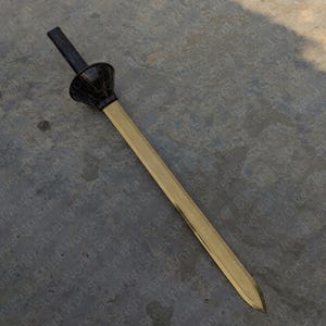 Puede incluir: Una espada con una hoja de color latón y un mango negro. El mango tiene un diseño acampanado en forma de copa. La hoja es larga y recta, con una punta. La espada parece estar hecha de metal.