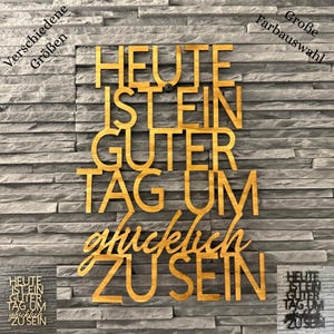 Könnte beinhalten: Ein Wand-Schriftzug aus Holz mit dem deutschen Text HEUTE IST EIN GUTER TAG UM glücklich ZU SEIN in einer Kombination aus Block- und Schreibschrift. Das Schild hat eine natürliche Holzoptik und ist an einer grauen Steinwand angebracht.