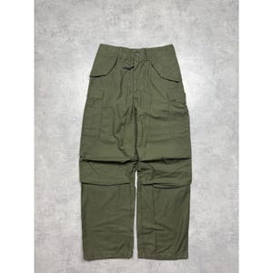 May include: Olive green cargo trousers with multiple pockets and a drawstring waist. The trousers have a relaxed fit and are made of a durable fabric. The design includes two large cargo pockets on the thighs and two pockets on the back.