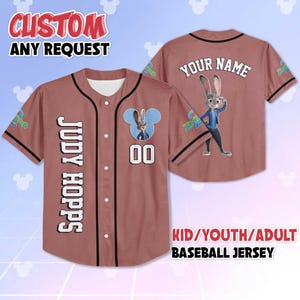 May include: A baseball jersey in a reddish-brown hue, featuring the text "JUDY HOPPS" vertically down the front. The jersey has a cartoon image of a rabbit and the number "00". The back of the jersey has the text "YOUR NAME". The top reads "CUSTOM ANY REQUEST".