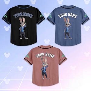 May include: Three baseball jerseys in black, blue, and mauve, each featuring a cartoon rabbit character and the text "YOUR NAME" on the back. The jerseys have contrasting sleeves and collar trim.