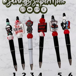 May include: Six black and white pens with decorative toppers. The toppers feature horror-themed characters and phrases, including a skull, Pennywise, and the words "True Crime Junkie" and "Horror Movie Addict".