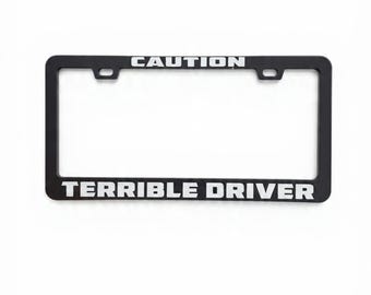 Marco de matrícula divertido con la frase "Conductor terrible" para coches y camiones.