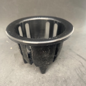 Può includere: Vaso per piante in plastica nera con un bordo rialzato e un motivo a griglia. Il vaso ha tre gambe.