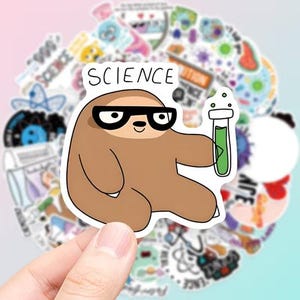 Op de afbeelding: Een gestanste vinylsticker met een bruine cartoonluiaard die een bril met zwart montuur draagt. De luiaard houdt een reageerbuis vast gevuld met groene vloeistof. Boven de luiaard staat het woord SCIENCE in zwarte, handgetekende hoofdletters.