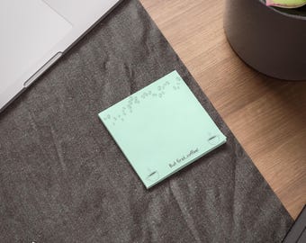 May include: A light green sticky note with a coffee cup and coffee beans design. The note says "But first, coffee!"