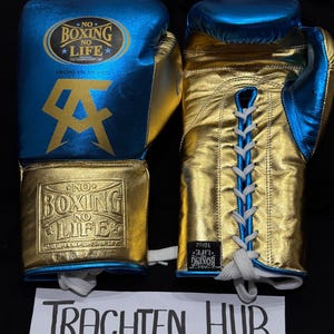 May include: A pair of blue and gold boxing gloves with white laces. The gloves have the text "No Boxing No Life" on them. The gloves are made in Mexico.