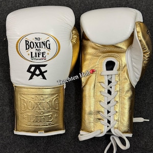 May include: A pair of white and gold boxing gloves with black laces. The gloves have the text "No Boxing No Life" and a logo on the front.