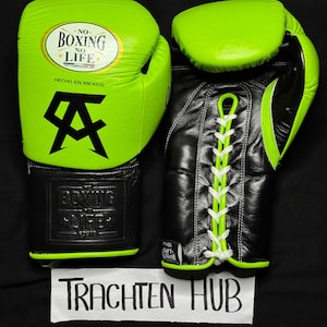 May include: A pair of black and neon green boxing gloves with white laces. The gloves have the text "No Boxing No Life" on the front and a logo with the letter "A" on the side. The gloves are made in Mexico.