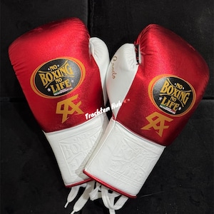 May include: Pair of red and white boxing gloves with white laces. The gloves have a gold logo that says "No Boxing No Life".