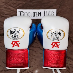 May include: A pair of white boxing gloves with red and blue accents. The gloves have the text "No Boxing No Life" on them. The gloves are tied together with a white string.