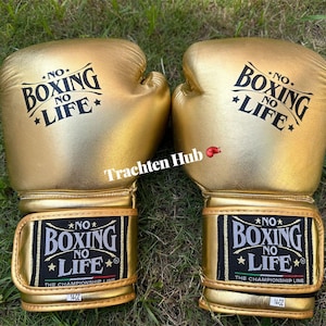 May include: A pair of gold boxing gloves with the text "NO BOXING NO LIFE" printed on them. The gloves have a black and gold wrist strap with the text "NO BOXING NO LIFE" and "THE CHAMPIONSHIP LINE". Each glove is 14 oz.