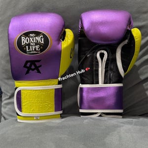 May include: Pair of boxing gloves with a purple metallic finish on the top and wrist strap, and yellow accents on the sides. The gloves have the text "NO BOXING NO LIFE" and a logo. The gloves are black and white on the inside.