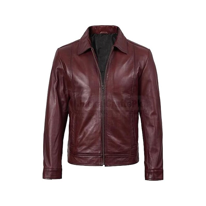 Puede incluir: Chaqueta de cuero burdeos con cuello y cremallera completa. La chaqueta tiene dos bolsillos delanteros y mangas largas. El forro interior es negro. La chaqueta se muestra sobre un fondo blanco.