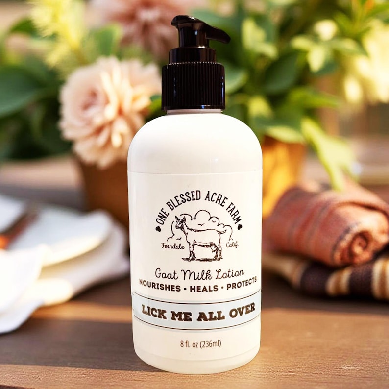 K&ouml;nnte beinhalten: Eine wei&szlig;e Lotionflasche mit schwarzem Pumpkopf. Das Etikett tr&auml;gt die Aufschrift "ONE BLESSED ACRE FARM" mit einer Ziegenillustration. Darunter steht "Goat Milk Lotion" und "LICK ME ALL OVER". Die Flasche enth&auml;lt 236 ml.