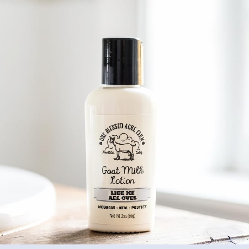 K&ouml;nnte beinhalten: Eine wei&szlig;e Flasche Ziegenmilch-Lotion mit schwarzem Verschluss. Das Etikett zeigt eine Ziegenillustration und den Text "The Blessed Acre Farm." Die Lotion ist 56g.