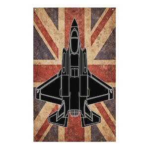 May include: A black jet fighter outline is centered on a distressed Union Jack flag background. The flag features red and white stripes and a blue field. The design has a vintage, worn appearance, with visible texture.