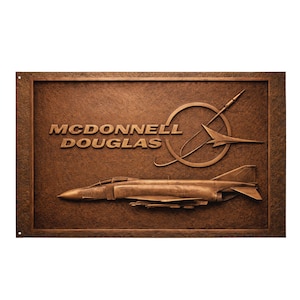 May include: A bronze plaque depicting a McDonnell Douglas F-4 Phantom II fighter jet in relief. The plaque features the text "McDonnell Douglas" and a stylized logo, set within a textured border, all in a bronze hue.