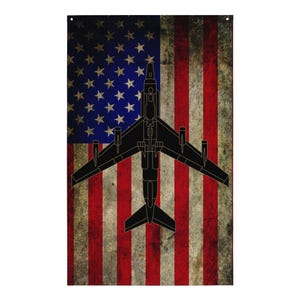 May include: A rectangular flag featuring the American flag with a distressed, vintage look. A black silhouette of a jet aircraft is centered over the flag. The flag has red and white stripes and a blue field with white stars.