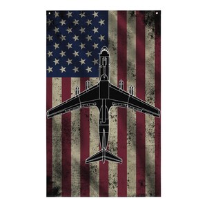 May include: A rectangular flag featuring the American flag with a distressed, vintage look. A black silhouette of an airplane is centered over the flag. The flag has red and white stripes and a blue field with white stars.