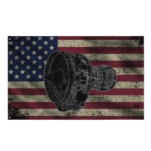 May include: A distressed American flag with a detailed black and white illustration of a jet engine. The flag features red and white stripes and a blue field with white stars. The jet engine is prominently displayed.