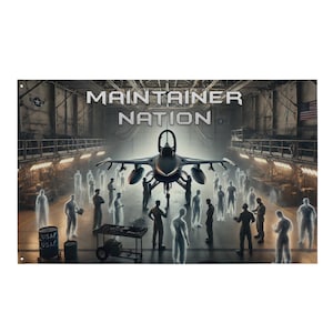 May include: A banner depicting a fighter jet in a hangar with the text "MAINTAINER NATION." Silhouetted figures surround the aircraft. The U.S. Air Force logo and American flag are visible. The banner has eyelets for hanging.